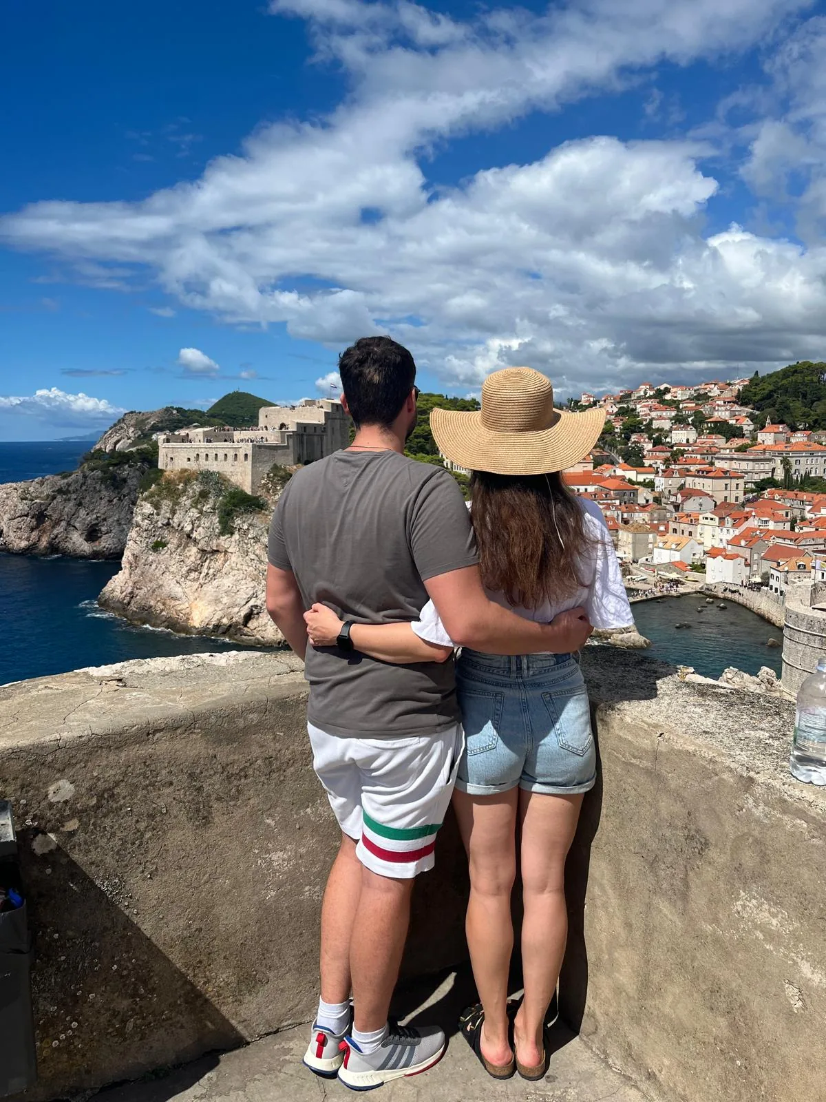 Anna and Mihael with their arms around each other, overlooking the sea and city